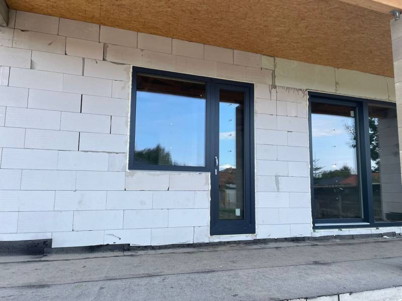 Nedokončená fasáda rodinného domu v Radavě s plastovými dveřmi a okny.