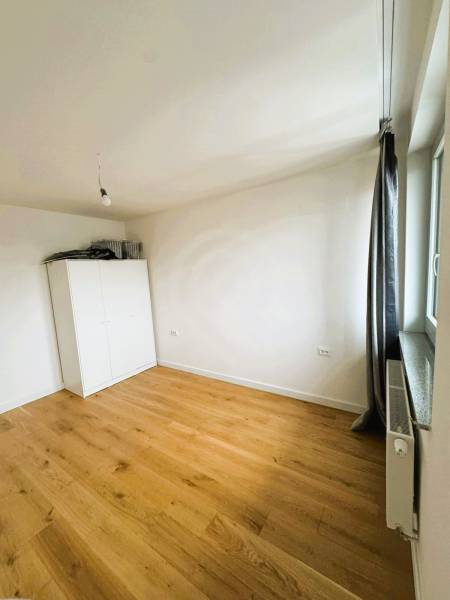 Pokoj v rodinném domě s bílou skříní a podlahou s dřevěným dekorem.