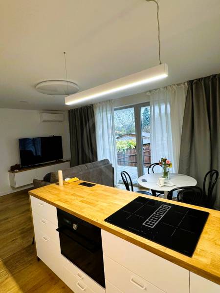 Kuchyňský ostrůvek s varnou deskou, jídelní stůl a pohovka v rodinném domě.