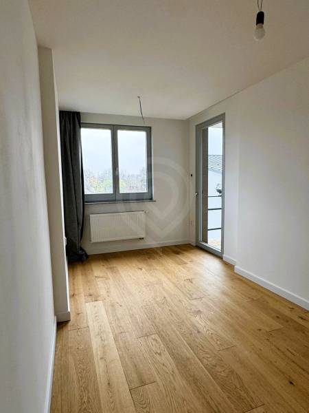 Pokoj v rodinném domě s podlahou s dřevěným dekorem a velkými okny.