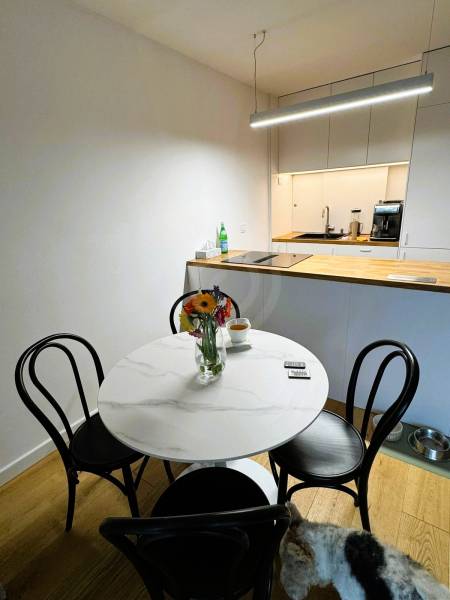 Jídelna v rodinném domě s kulatým stolem, květinami a podlahou s dřevěným dekorem.