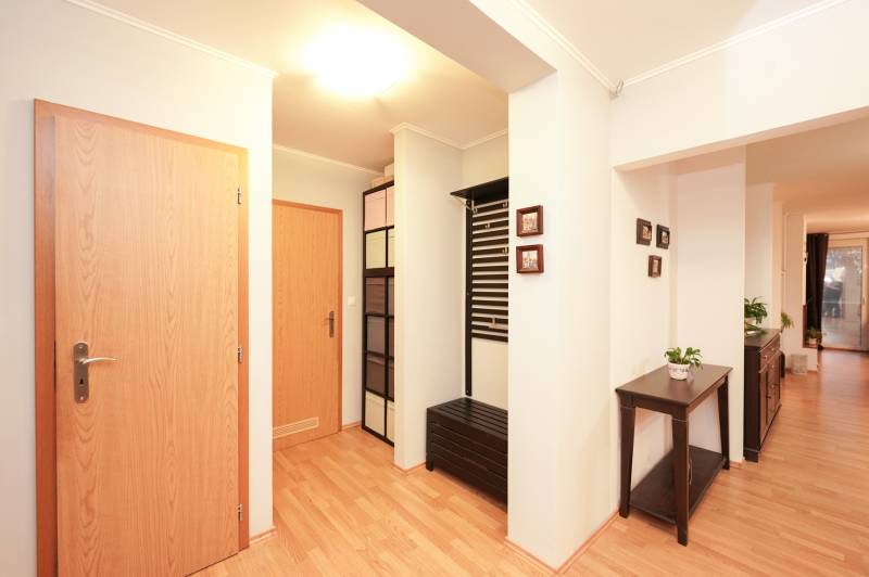 Interiér rodinného domu s podlahou s dřevěným dekorem, barevnými skříňkami a květináčem.