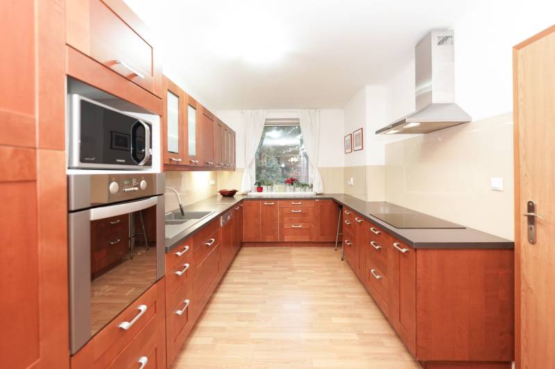 Kuchyně v rodinném domě s dřevěným dekorem, s varnou deskou a mikrovlnnou troubou.