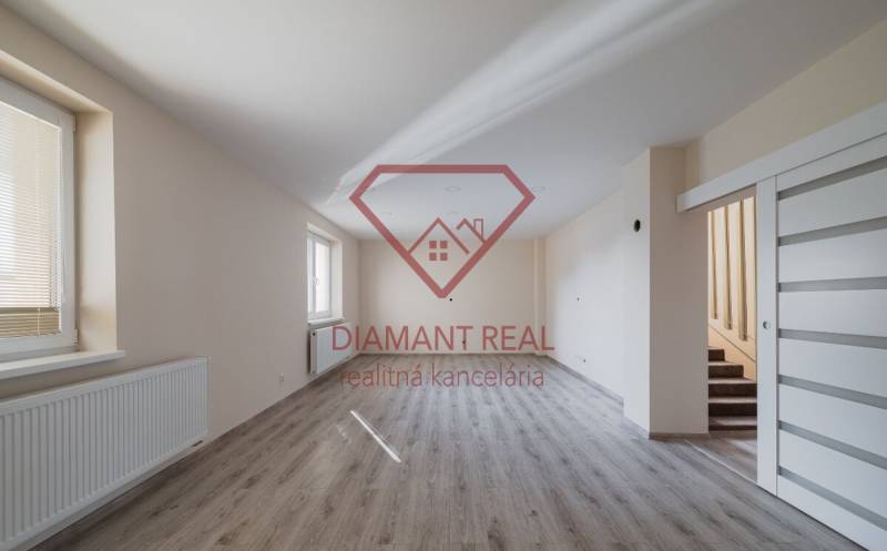 Prostorná místnost s podlahou s dřevěným dekorem a schodištěm v rodinném domě.