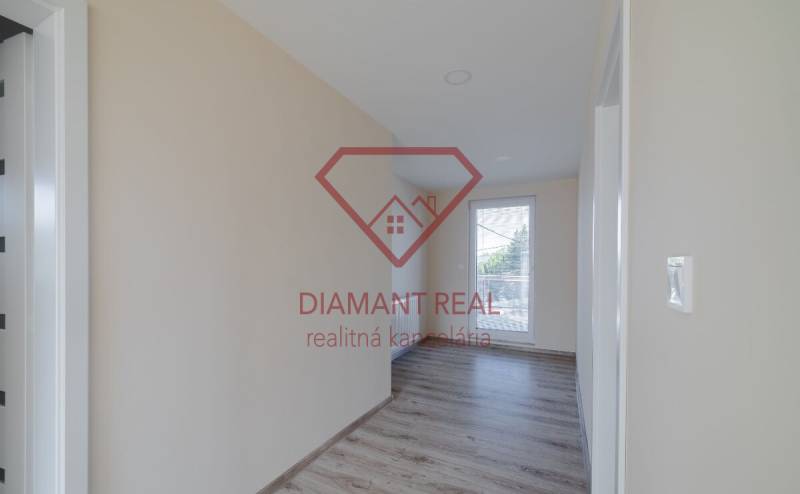 Chodba v rodinném domě s podlahou s dřevěným dekorem a velkým oknem.