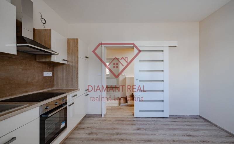 Kuchyně v rodinném domě s dřevěným dekorem, bílá vestavěná skříň, posuvné dveře.