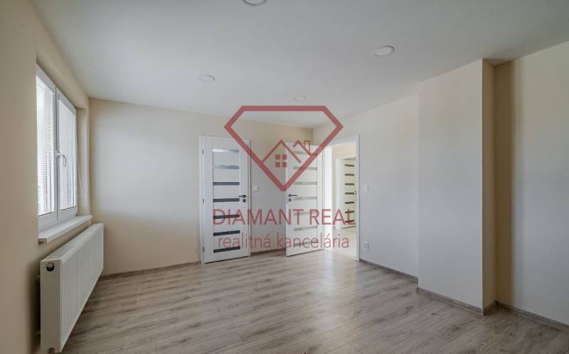 Pokoj v rodinném domě s podlahou s dřevěným dekorem, světlými stěnami a oknem.