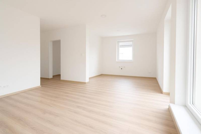 Bílý interiér rodinného domu s podlahou s dřevěným dekorem a velkým oknem.