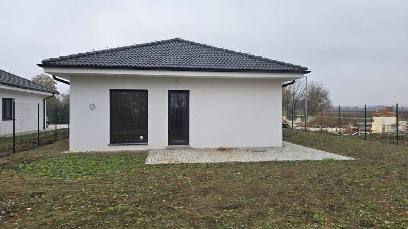 Rodinný dům v Cíferi s bílou fasádou a terasou v zahradě.