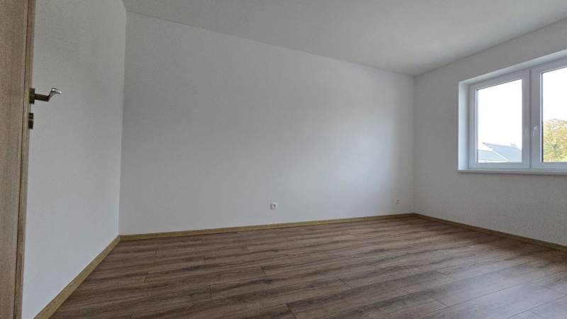 Pokoj v rodinném domě s podlahou s dřevěným dekorem a velkým oknem.