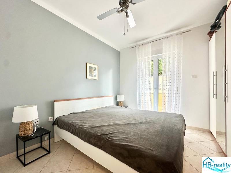 Ložnice v rekreačním apartmánu s manželskou postelí a nočními stolky.