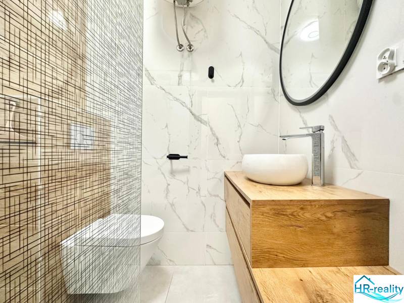 Koupelna v rekreačním apartmánu s minimalistickým designem a výrazným dřevěným dekorem.
