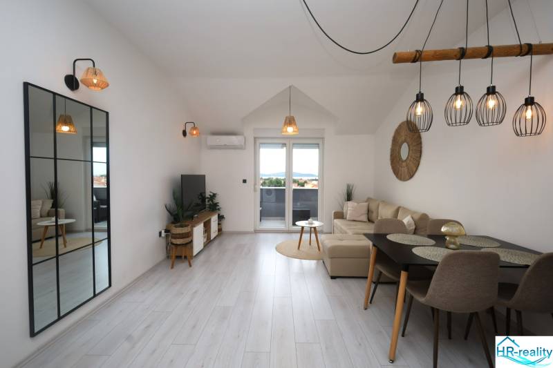 Obývací pokoj v rekreačním apartmánu s podlahou s dřevěným dekorem a velkým zrcadlem.