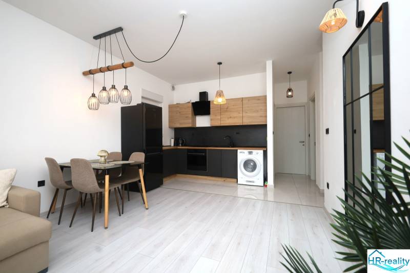 Kuchyně v rekreačním apartmánu s jídelním stolem a podlahou s dřevěným dekorem.