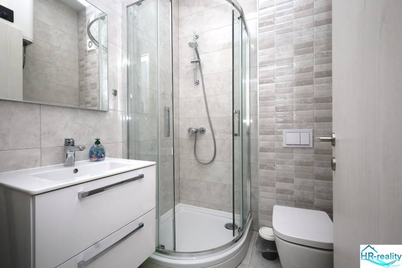 Koupelna v Rekreačním apartmánu s moderním sprchovým koutem a minimalistickým zařízením.