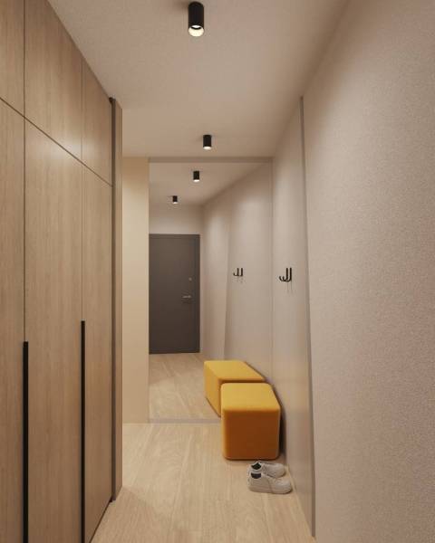 Interiér budovy s podlahou s dřevěným dekorem, šatník, zrcadlo a žluté sezení.