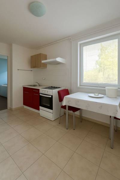 Kuchyně s červenou skříňkou, stolem a dvěma židlemi v rodinném domě.