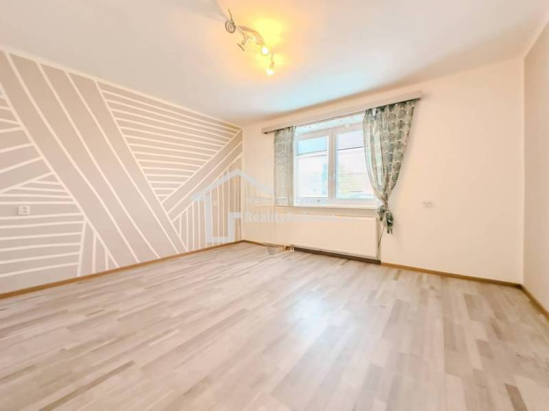 Pokoj v rodinném domě s geometrickou malbou a podlahou s dřevěným dekorem.