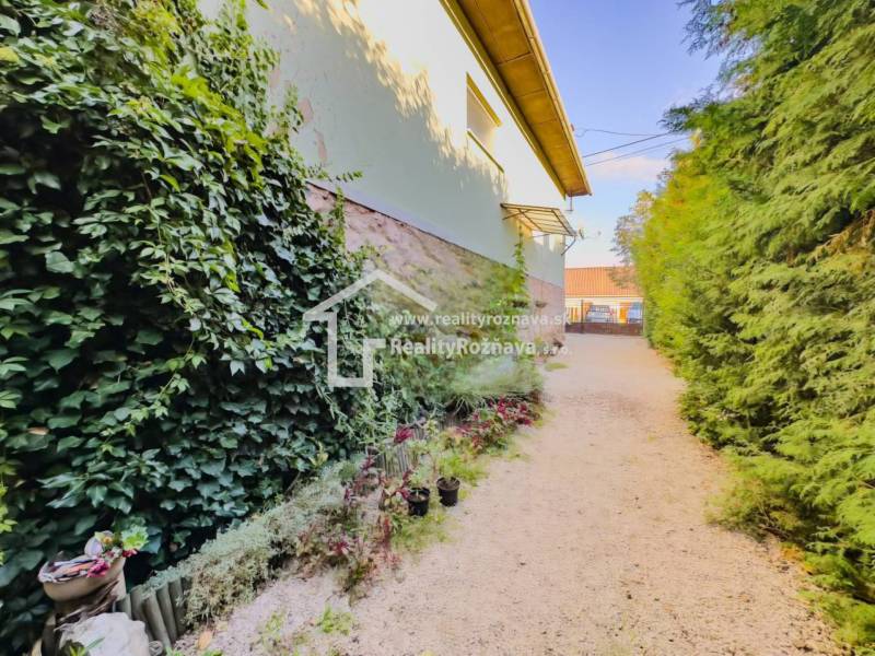 Zahrada u rodinného domu v Betliari s bohatým porostem a květinovými dekoracemi.