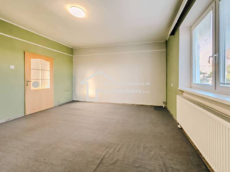 Interiér rodinného domu s barevnými stěnami, kobercem a oknem se žaluziemi.