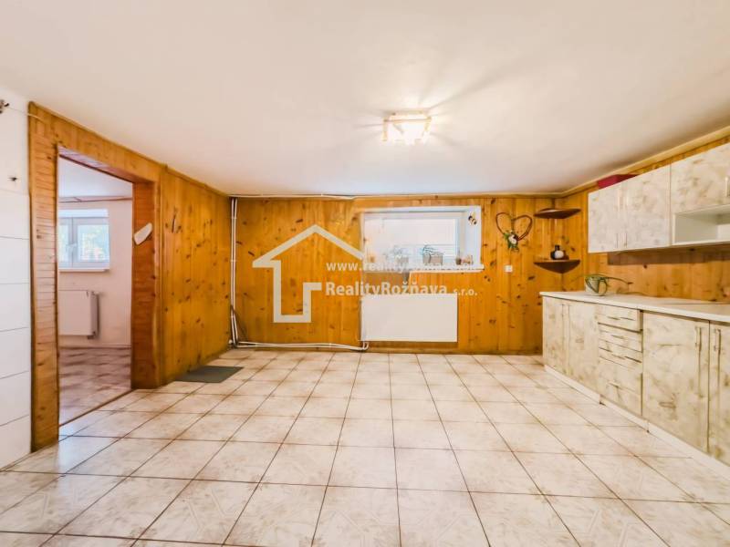 Kuchyně v rodinném domě s dřevěným dekorem a keramickou dlažbou.