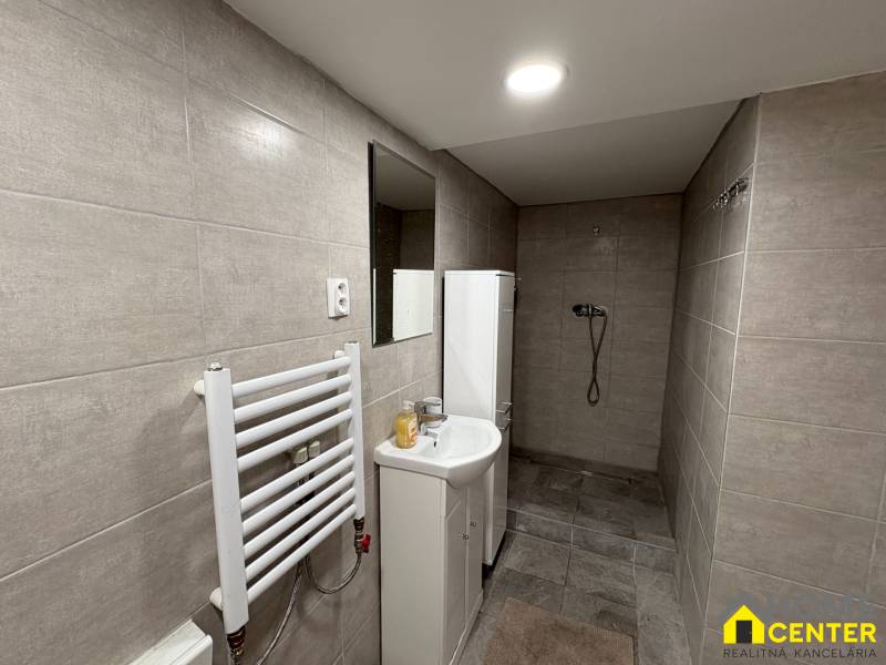 Koupelna v 1-pokojovém bytě s obklady ve světlých odstínech a sprchovým koutem.