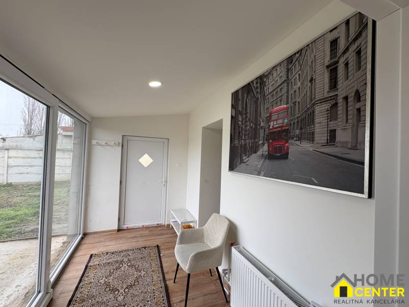 Interiér 1-pokojového bytu s podlahou s dřevěným dekorem, skleněnými dveřmi a uměním na stěně.