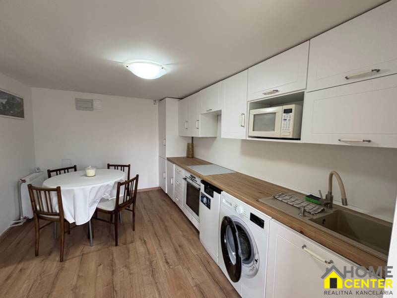 Kuchyně v 1-pokojovém bytě s podlahou s dřevěným dekorem a jídelním stolem.