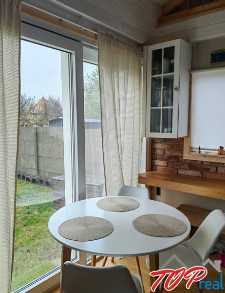 Jídelní kout v rodinném domě s podlahou s dřevěným dekorem, cihlovou stěnou a velkými okny.