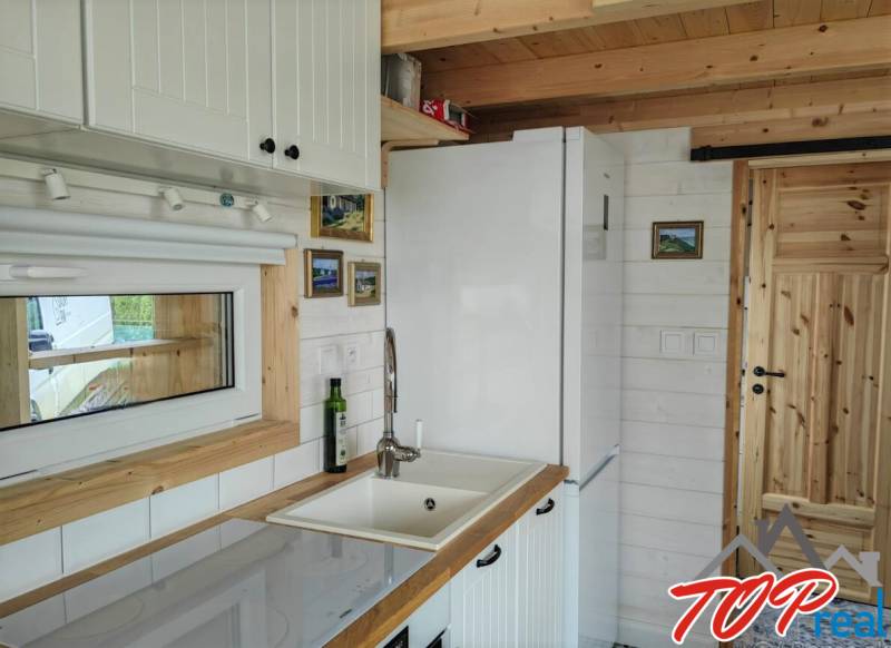 Kuchyně v rodinném domě s bílým nábytkem a dřevěnými prvky.