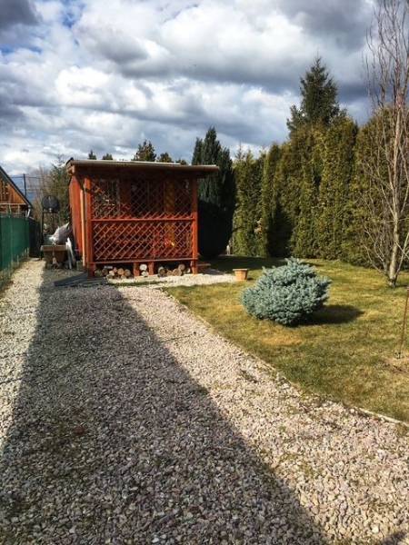 Dřevěná chata v Kráľovej nad Váhom s upravenou zahradou a keřem.