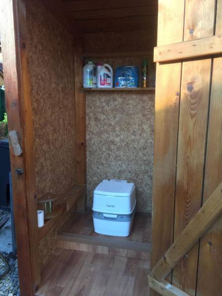 Dřevěná chata v Kráľovej nad Váhom s chemickým WC a poličkou.