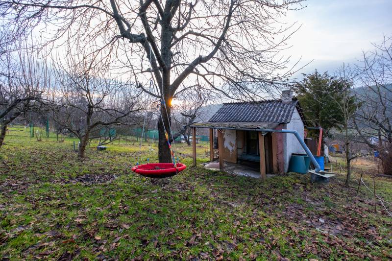 Zahrada s malou chatkou v Prešově a visící houpačkou na stromě.