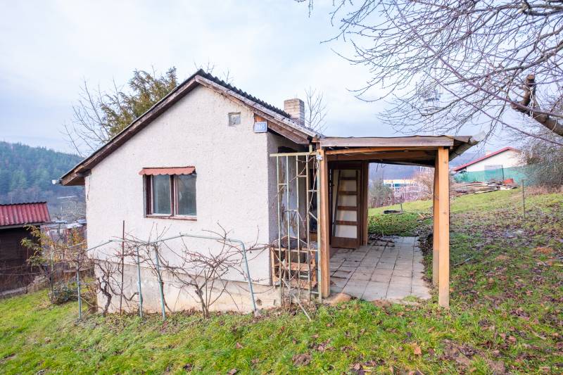 Chata v Prešově s dřevěnou konstrukcí a vinicí na travnatém kopci.