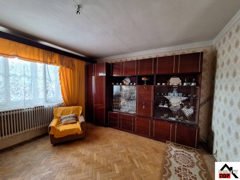 Obývací pokoj v rodinném domě s křeslem, nábytkem a podlahou s dřevěným dekorem.