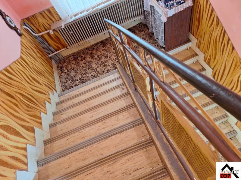 Schodiště s kobercem a podlahou s dřevěným dekorem v rodinném domě.