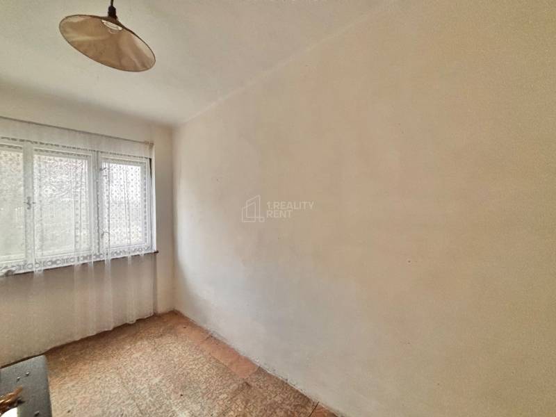 Pokoj v rodinném domě s jedním oknem a závěsem, s kobercovou podlahou.