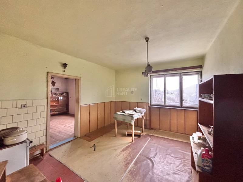 Interiér rodinného domu s nábytkem, oknem a podlahou s dřevěným dekorem.