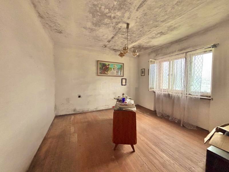 Pokoj v rodinném domě s jednoduchým nábytkem a podlahou s dřevěným dekorem.