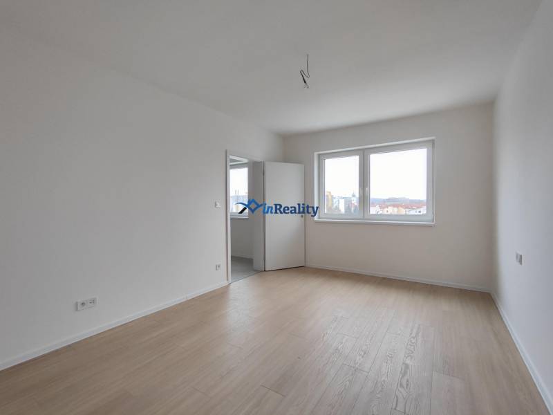 Světlý pokoj s podlahou s dřevěným dekorem v 2pokojovém bytě.