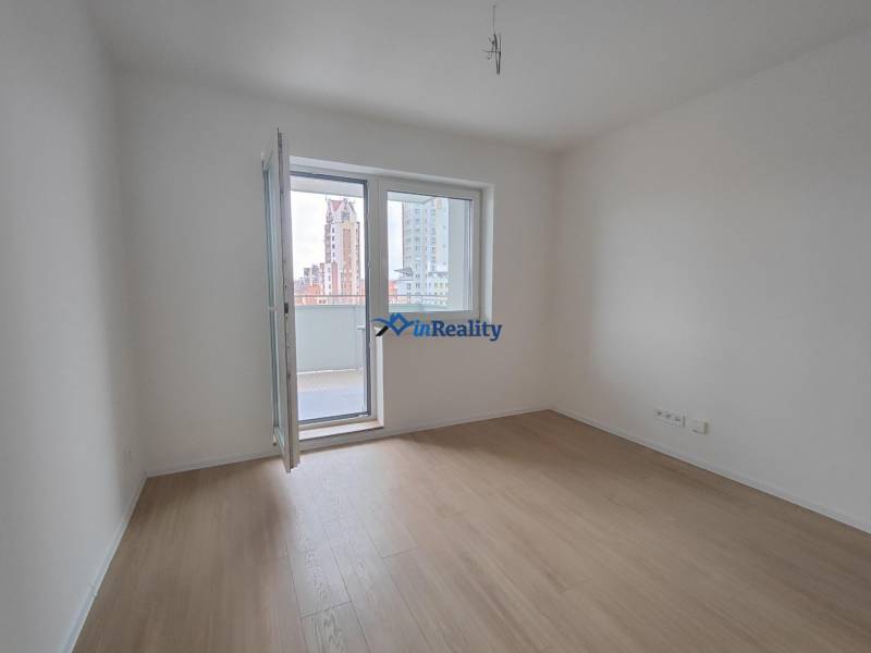 Pokoj v 2-pokojovém bytě s podlahou s dřevěným dekorem a balkonem.