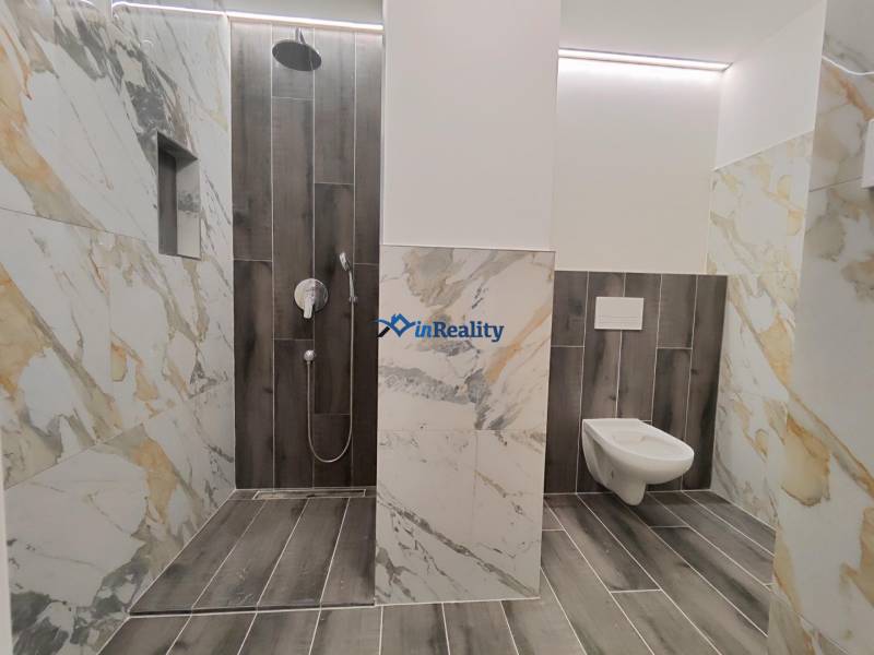 Koupelna v 2-pokojovém bytě s mramorovými obklady a podlahou s dřevěným dekorem.