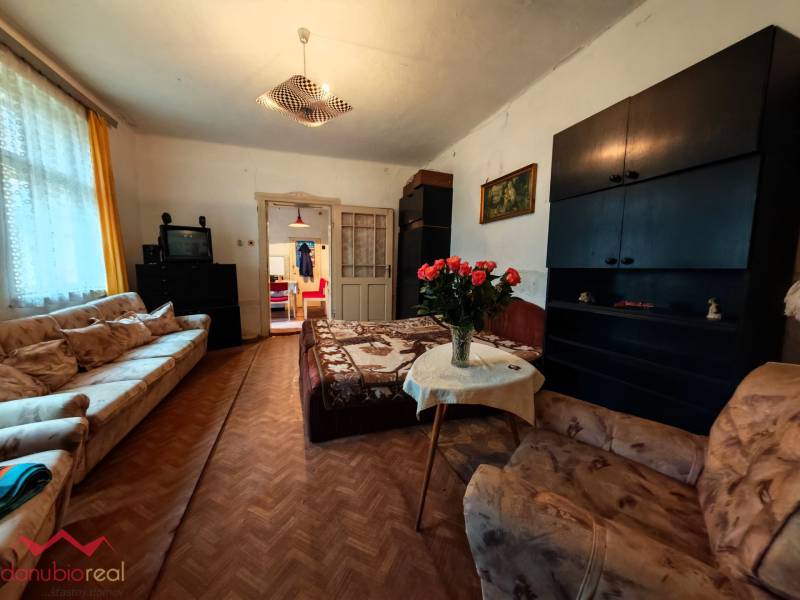 Obývací pokoj v rodinném domě s pohovkami, TV a podlahou s dřevěným dekorem.