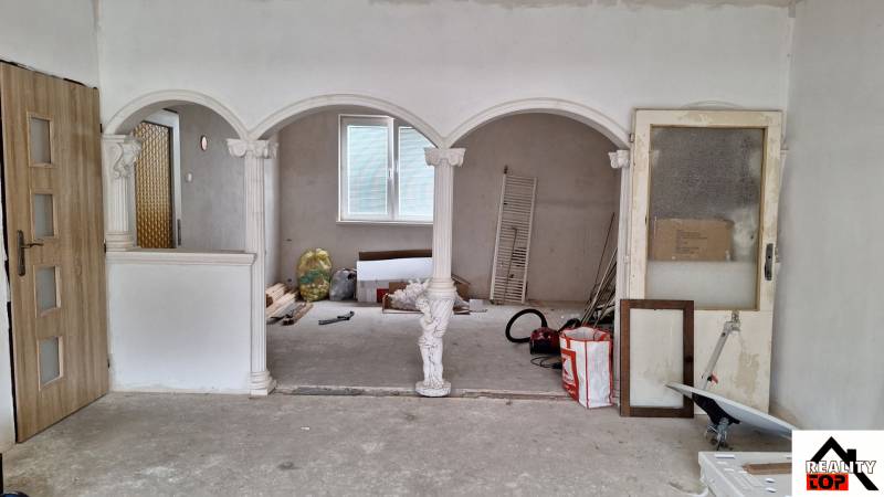 Interiér rodinného domu s oblouky a sloupy, neúplná renovace.