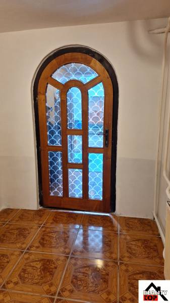 Klenuté dřevěné dveře se vzorovaným sklem v rodinném domě, podlaha s dřevěným dekorem.