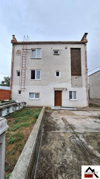 Rodinný dům v Zacharovcích s jednoduchou fasádou, okny a venkovním schodištěm.