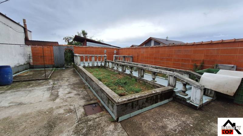 Dvůr rodinného domu v Zacharovcích s květinovým záhonem a betonovým chodníkem.