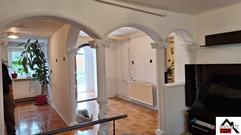 Interiér rodinného domu s obloukovými sloupy a podlahou s dřevěným dekorem.