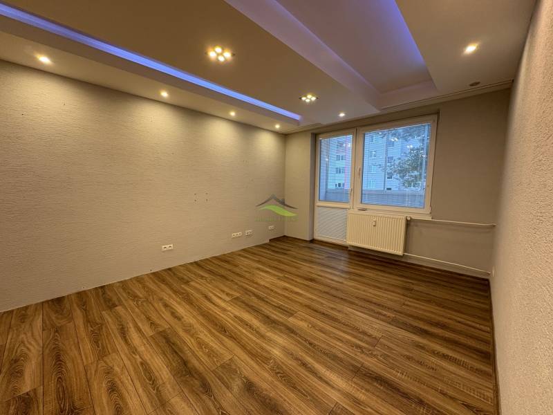 Pokoj v 3-pokojovém bytě s podlahou s dřevěným dekorem a bodovým osvětlením.