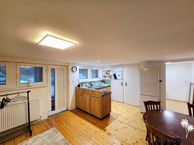 Kuchyňa v 1-pokojovém bytě s podlahou s dřevěným dekorem a stolem.